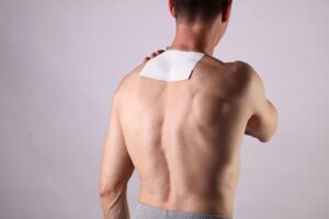 Man applying pain relief patch on his back