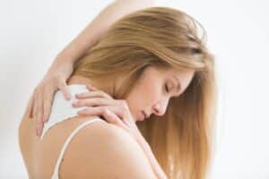 Woman applying pain relief patch on her back