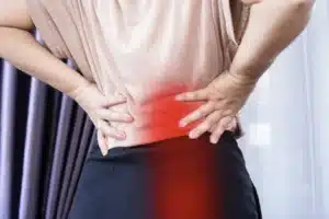 Woman holding her lower back and glutes in pain, demonstrating symptoms that require effective sciatica treatment in Singapore.