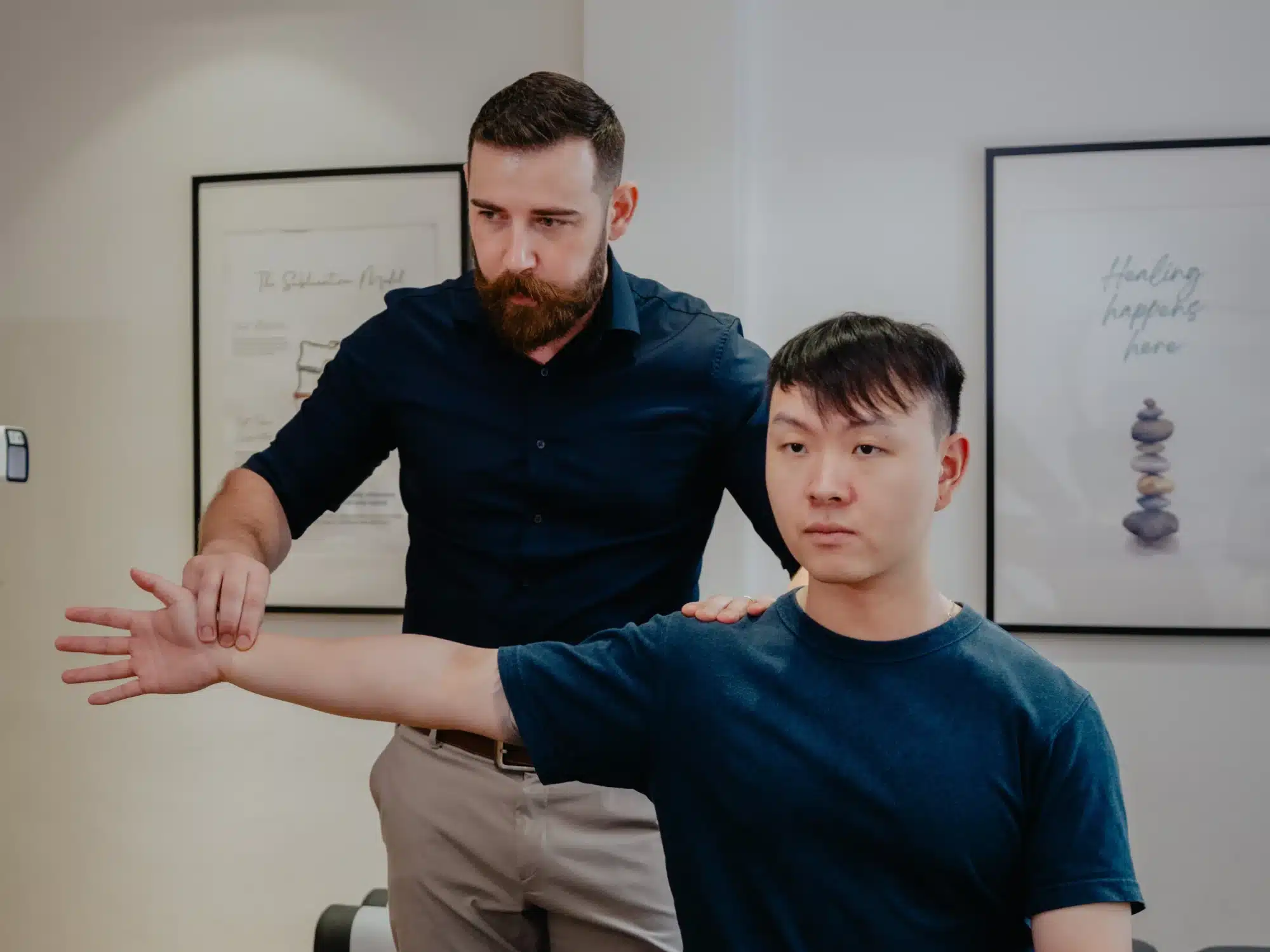 A patient's arm being assessed by a male doctor during an elbow pain Chiropractor Singapore appointment.